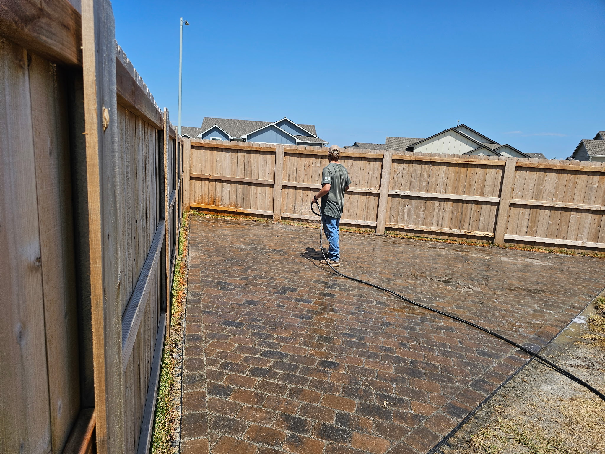 Completed outdoor project with custom paved patio, wooden fence, and swings